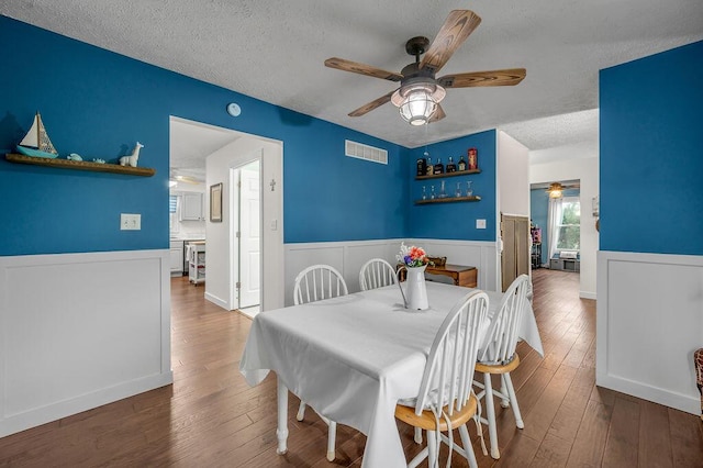 dining area featuring ceiling fan, wood-type flooring, and a textured ceiling