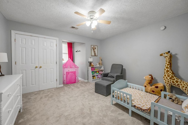 carpeted bedroom with ceiling fan, a closet, and a textured ceiling