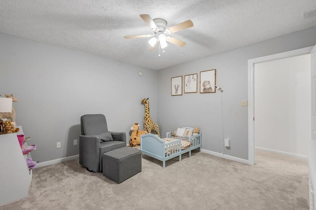 sitting room featuring light carpet, a textured ceiling, and ceiling fan