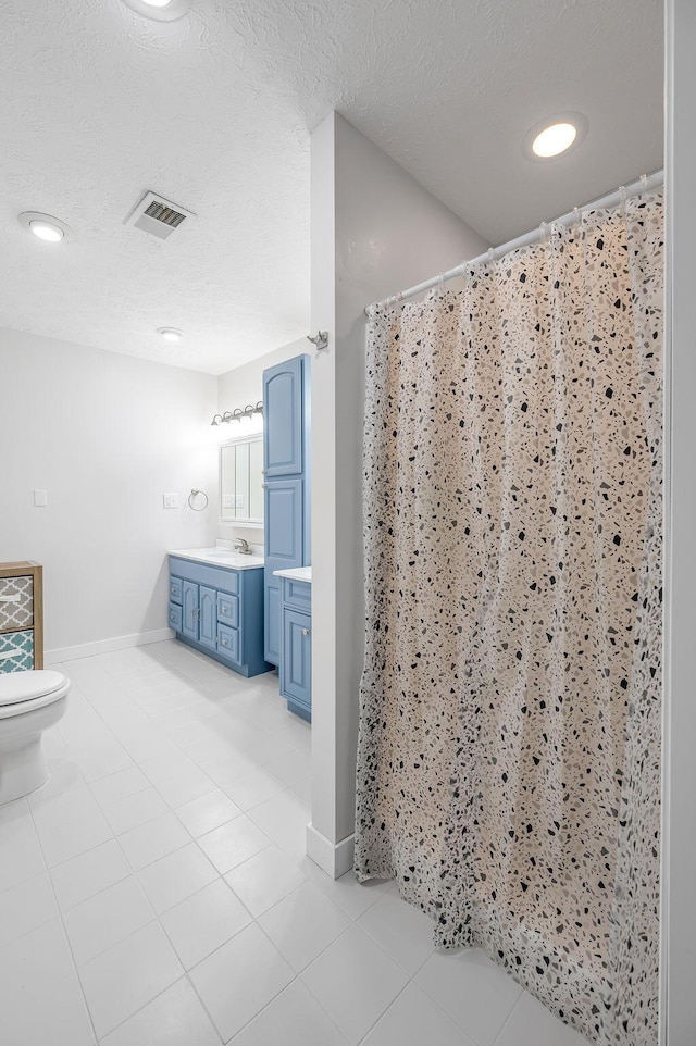 bathroom featuring a textured ceiling, vanity, tile patterned flooring, toilet, and curtained shower