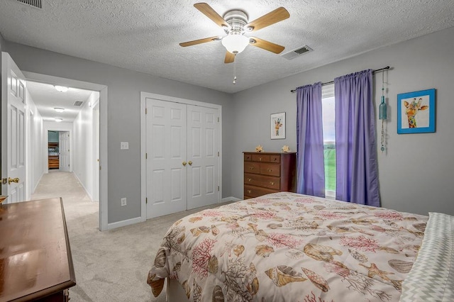 carpeted bedroom featuring ceiling fan, a textured ceiling, and a closet