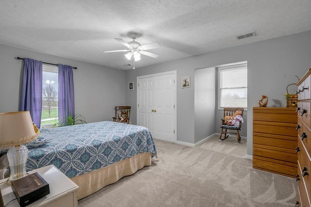 bedroom with ceiling fan, light carpet, and a textured ceiling