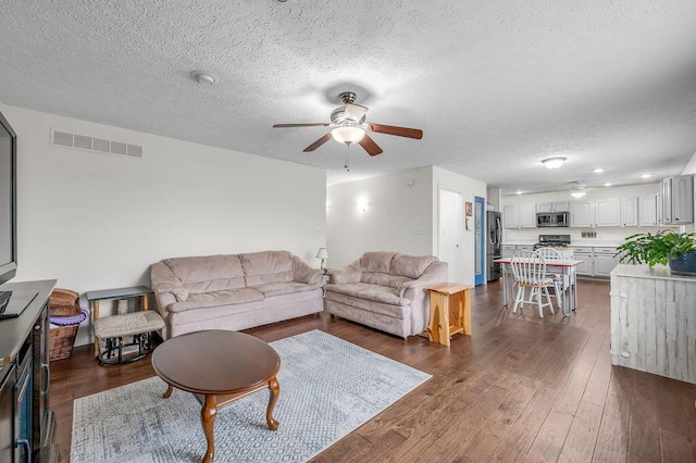 living room featuring a textured ceiling, dark hardwood / wood-style flooring, and ceiling fan