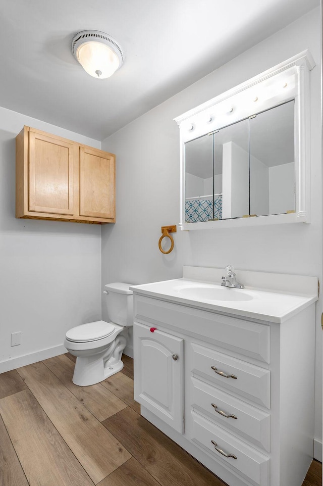 bathroom with hardwood / wood-style floors, vanity, and toilet