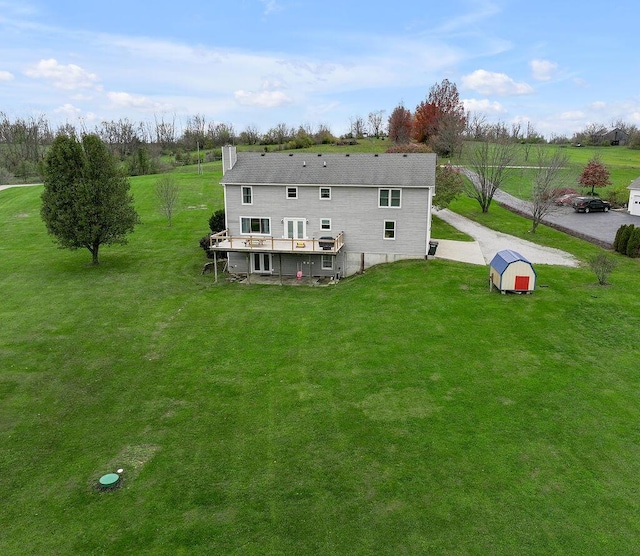 rear view of property with a lawn, a wooden deck, and a storage shed