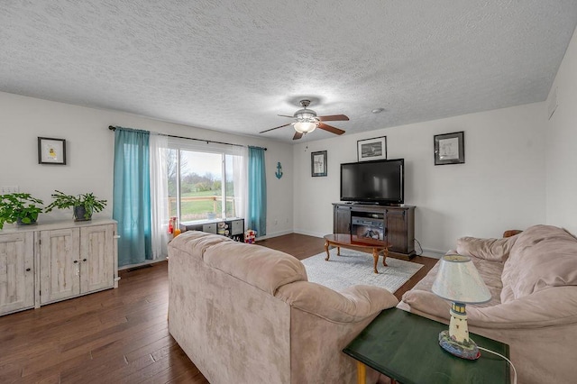 living room featuring a textured ceiling, ceiling fan, and dark wood-type flooring