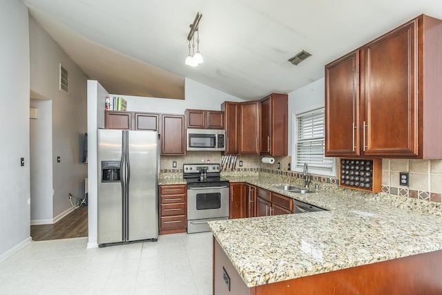 kitchen with sink, light stone counters, decorative light fixtures, appliances with stainless steel finishes, and kitchen peninsula