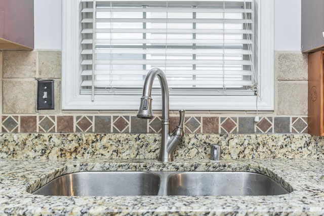 kitchen with sink, light stone counters, and decorative backsplash