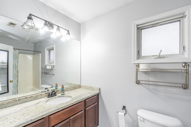 bathroom featuring walk in shower, vanity, and toilet