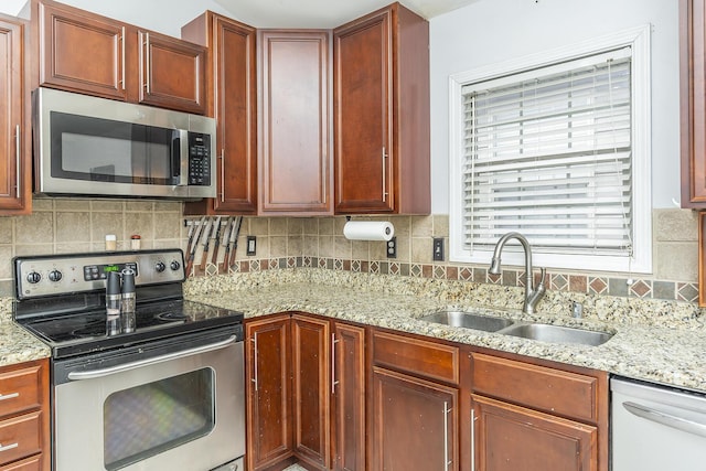 kitchen featuring tasteful backsplash, stainless steel appliances, light stone countertops, and sink