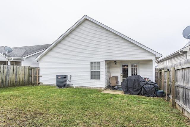 rear view of house featuring a yard, cooling unit, and french doors