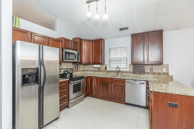 kitchen with sink, hanging light fixtures, appliances with stainless steel finishes, kitchen peninsula, and decorative backsplash