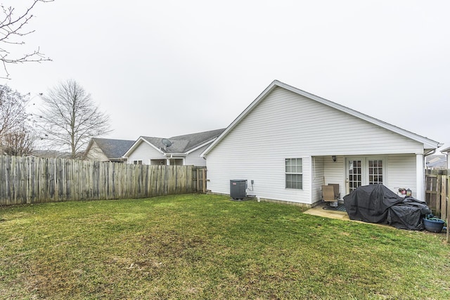 rear view of property with central AC, a patio area, and a lawn