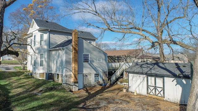 back of property with a yard, a storage shed, and central air condition unit