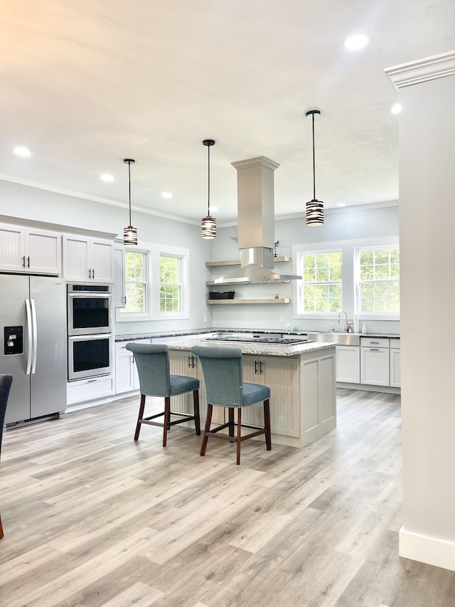 kitchen featuring pendant lighting, white cabinets, appliances with stainless steel finishes, a kitchen island, and island exhaust hood