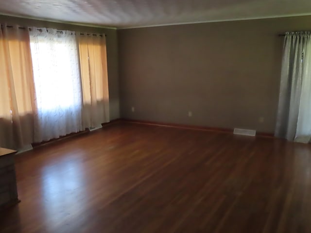 empty room featuring dark hardwood / wood-style flooring and crown molding