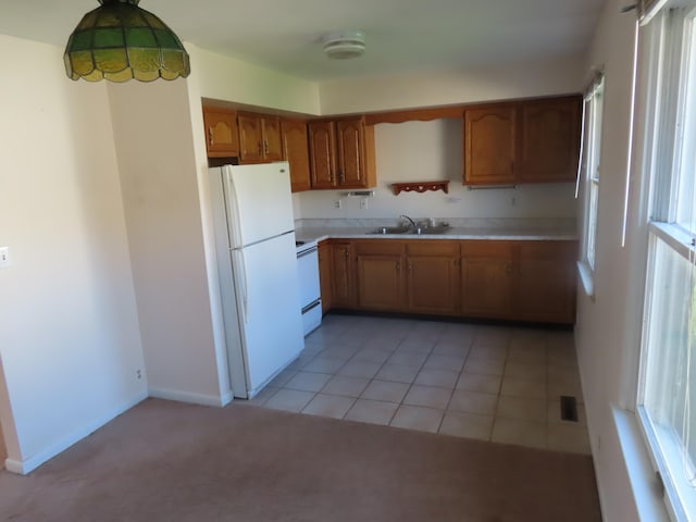 kitchen featuring a healthy amount of sunlight, light colored carpet, white appliances, and sink