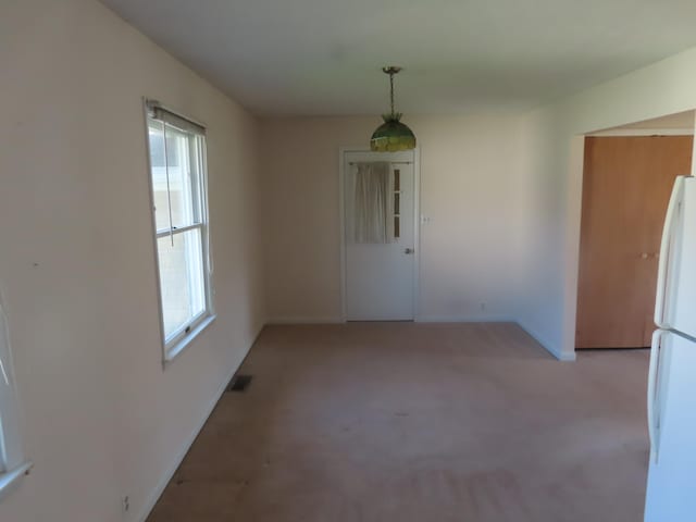 unfurnished dining area with light colored carpet