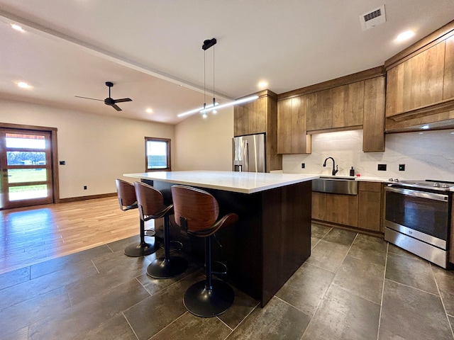 kitchen with pendant lighting, sink, appliances with stainless steel finishes, backsplash, and a kitchen island