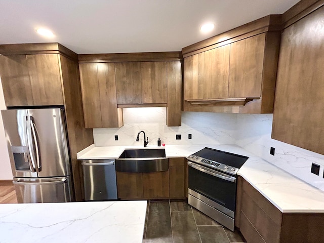 kitchen featuring light stone countertops, sink, dark hardwood / wood-style floors, decorative backsplash, and appliances with stainless steel finishes