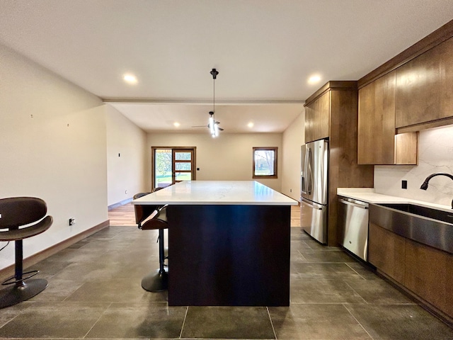 kitchen featuring ceiling fan, a center island, stainless steel appliances, pendant lighting, and a kitchen bar