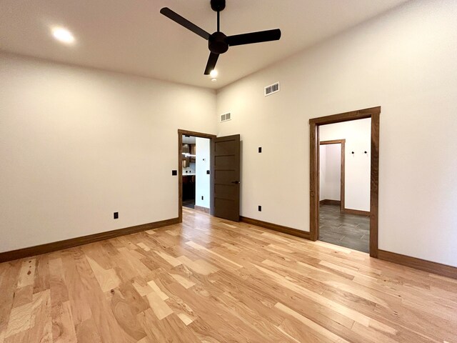 unfurnished bedroom featuring ceiling fan, a towering ceiling, and light hardwood / wood-style flooring