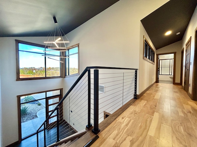 corridor featuring lofted ceiling, a chandelier, and light hardwood / wood-style flooring