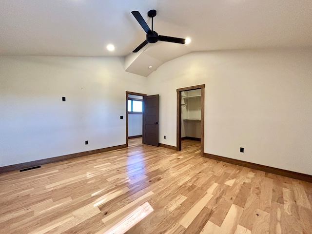 unfurnished bedroom featuring vaulted ceiling, a spacious closet, ceiling fan, and light hardwood / wood-style flooring