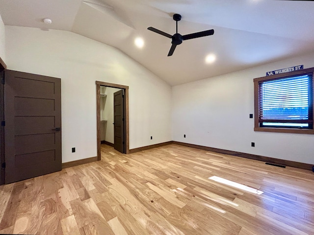 unfurnished bedroom with ceiling fan, a spacious closet, light hardwood / wood-style floors, and vaulted ceiling