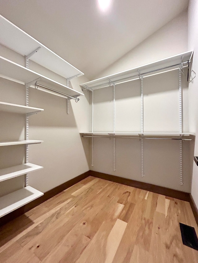 walk in closet with hardwood / wood-style flooring and lofted ceiling