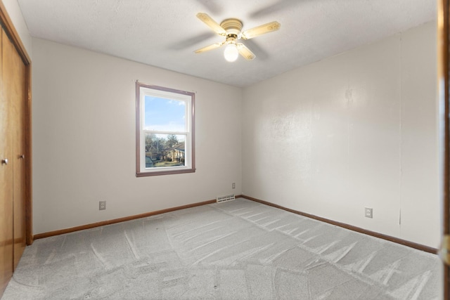 carpeted empty room with ceiling fan and a textured ceiling