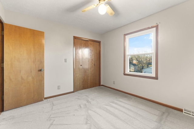 unfurnished bedroom with ceiling fan, light colored carpet, and a closet