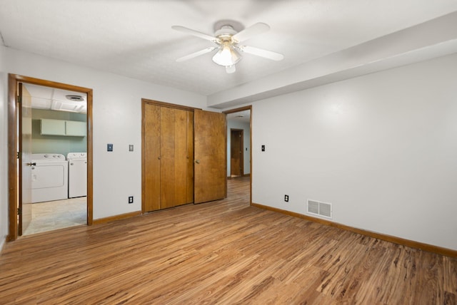 unfurnished bedroom featuring washer and clothes dryer, a closet, ceiling fan, and light wood-type flooring