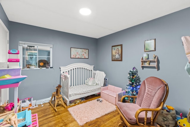 bedroom with hardwood / wood-style flooring and a crib