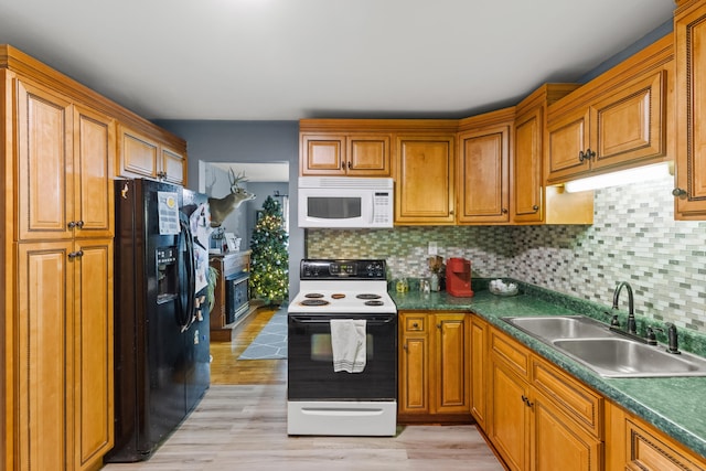 kitchen with light wood-type flooring, white appliances, sink, and tasteful backsplash