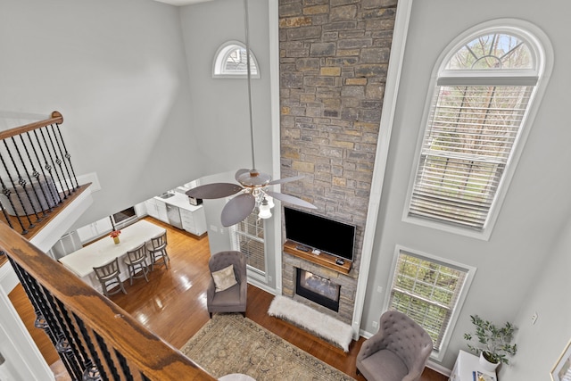 living room featuring a wealth of natural light, a fireplace, a high ceiling, and hardwood / wood-style flooring