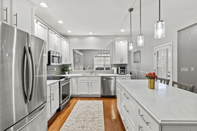 kitchen with stainless steel appliances, white cabinetry, a kitchen island, and sink