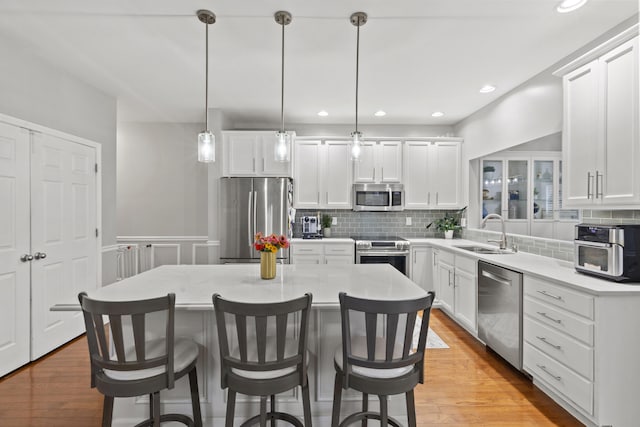 kitchen featuring pendant lighting, light hardwood / wood-style floors, sink, and appliances with stainless steel finishes