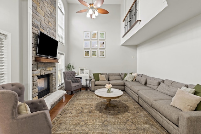 living room with hardwood / wood-style floors, a healthy amount of sunlight, a stone fireplace, and a high ceiling