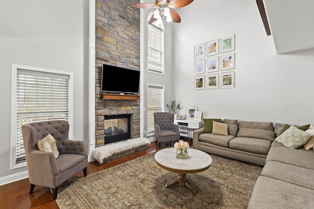 living room with dark hardwood / wood-style flooring, ceiling fan, beam ceiling, high vaulted ceiling, and a fireplace