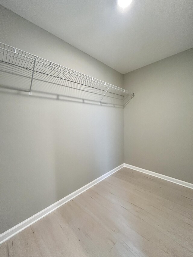 full bathroom featuring baseboards, ceiling fan, a marble finish shower, and wood finished floors