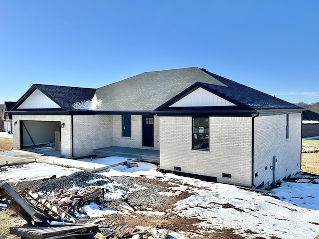 view of front facade featuring crawl space, an attached garage, roof with shingles, and brick siding