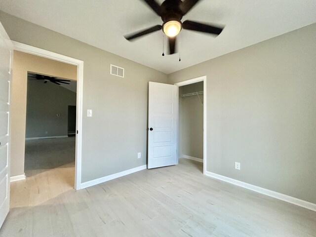 unfurnished bedroom with light wood finished floors, visible vents, baseboards, a ceiling fan, and a closet