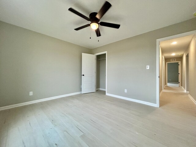 unfurnished bedroom with a closet, visible vents, light wood-style flooring, ceiling fan, and baseboards