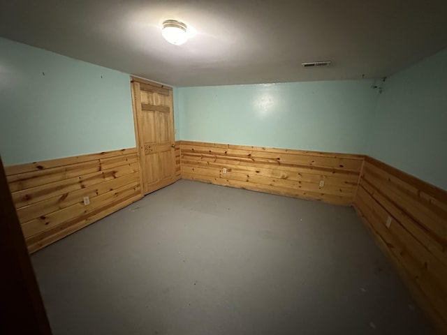 unfurnished room featuring concrete flooring and wooden walls