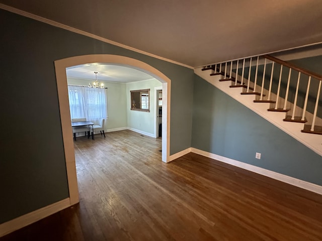 spare room featuring a notable chandelier, wood-type flooring, and crown molding