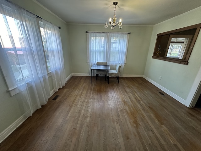 unfurnished dining area with dark hardwood / wood-style floors, crown molding, and a chandelier