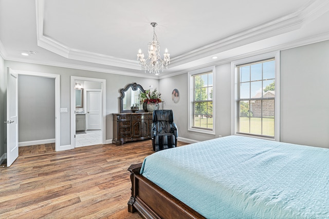 bedroom with wood-type flooring, connected bathroom, a raised ceiling, and crown molding