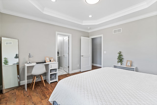 bedroom with dark hardwood / wood-style floors, ornamental molding, connected bathroom, and a tray ceiling