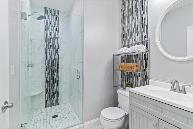 bathroom featuring vanity, a shower with shower door, and toilet